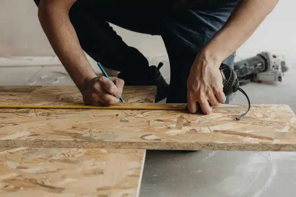 A builder begins measuring planks of wood for a new home in Calgary